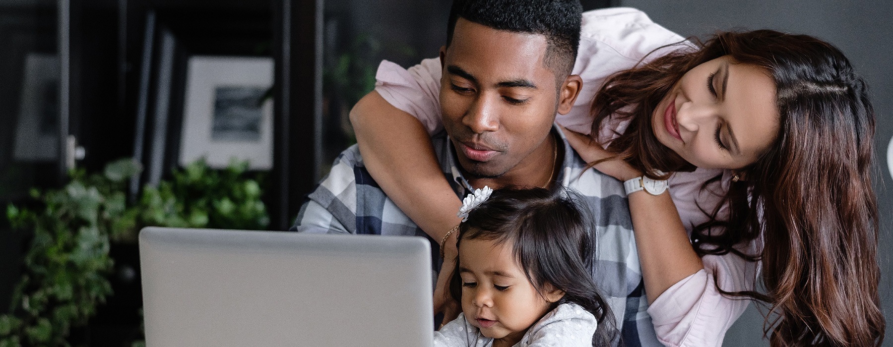 lifestyle image of a couple and child looking at a laptop together